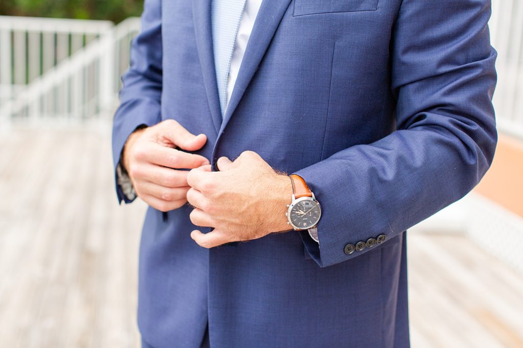 Groom buttoning his jacket with a watch