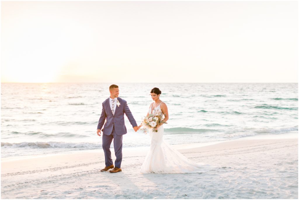 bride and groom walking on beach holding hands