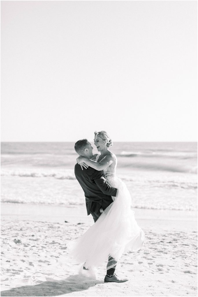 Groom twirling bride on beach