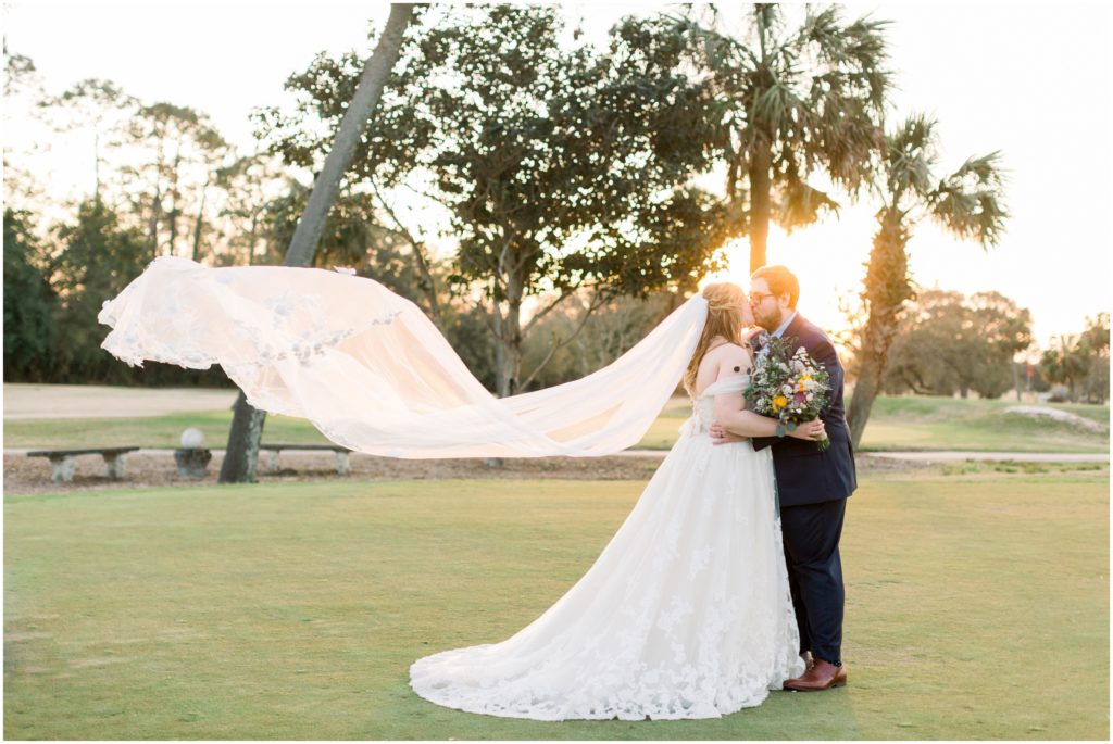 sunset veil floating in the wind with bride and groom