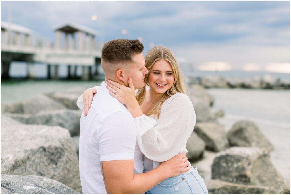 girl putting her arms around a guy while sitting on the rocks